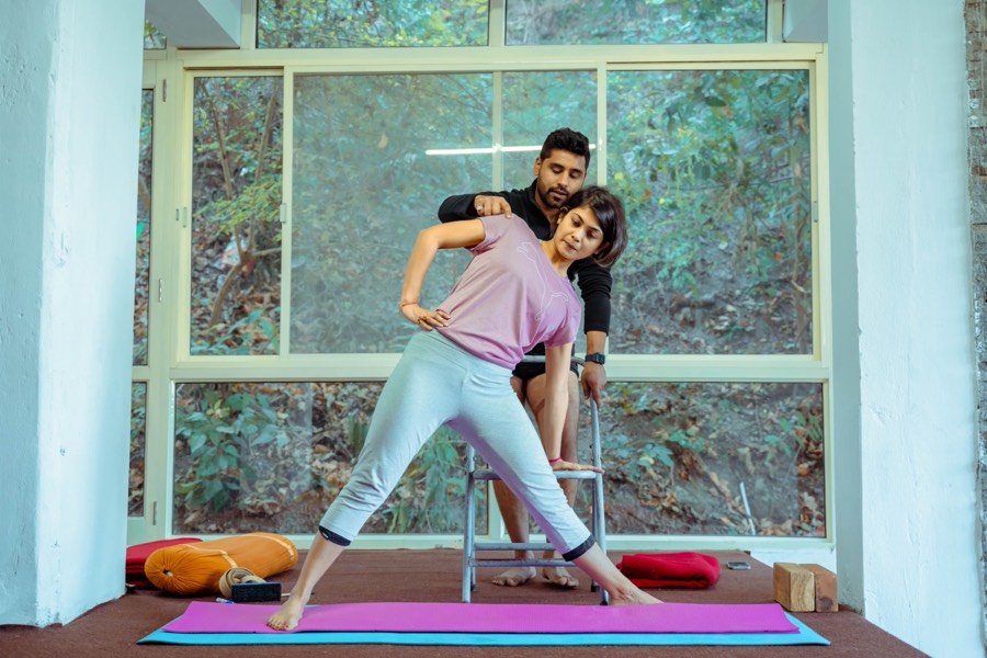 Yoga instructor adjusting a student mid-pose