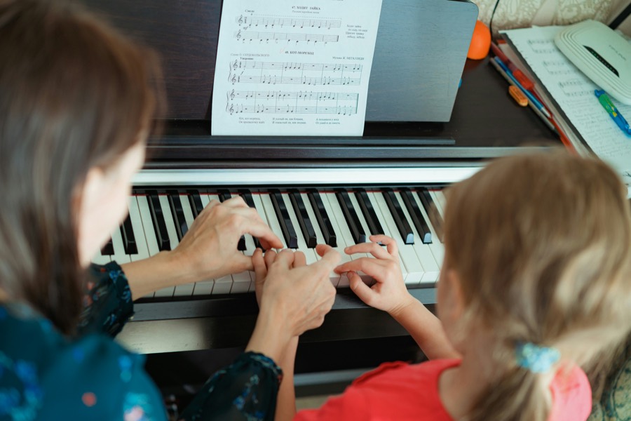 Piano teacher guiding a child's hands on the keys